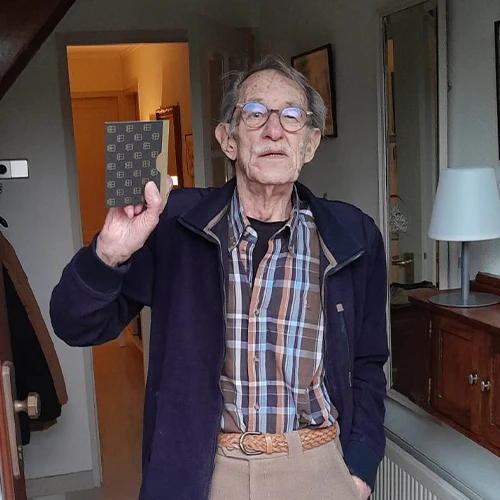 Meneer Rongen in de deuropening van zijn woning, met in zijn hand de gewonnen VVV-cadeaukaart