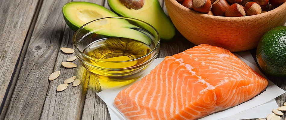 Tafel bedekt met olie, zalmfilet, avocado en hazelnoten