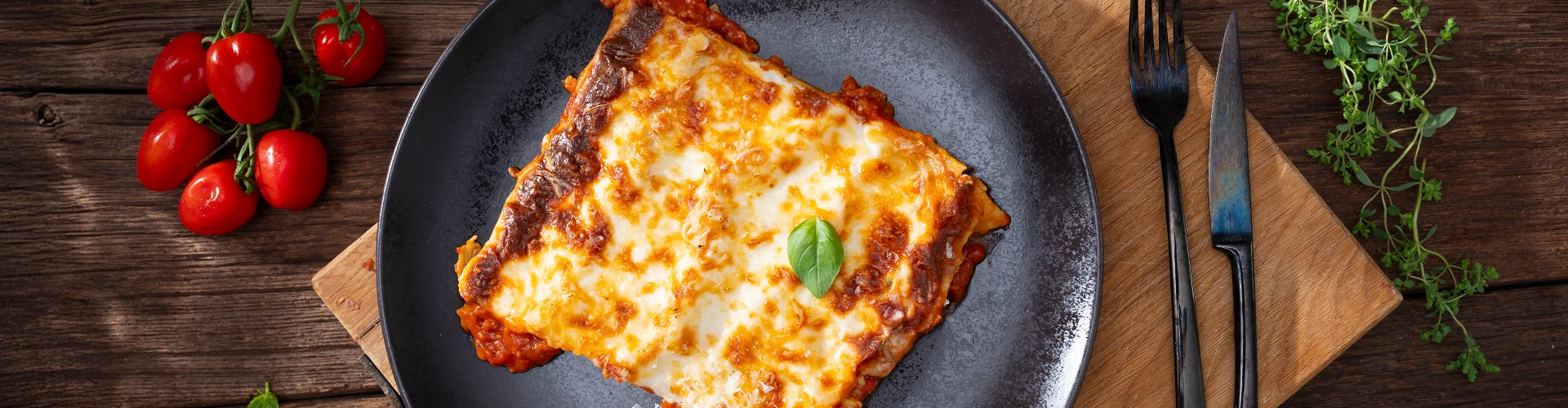 Bord met lasagne en cherrytomaatjes en bestek